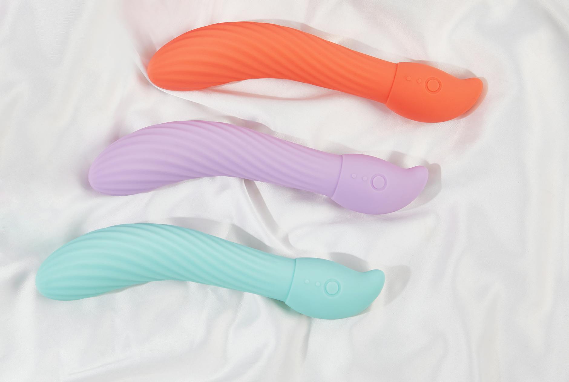 Studio arrangement of colorful vibrators and toys on white fabric
