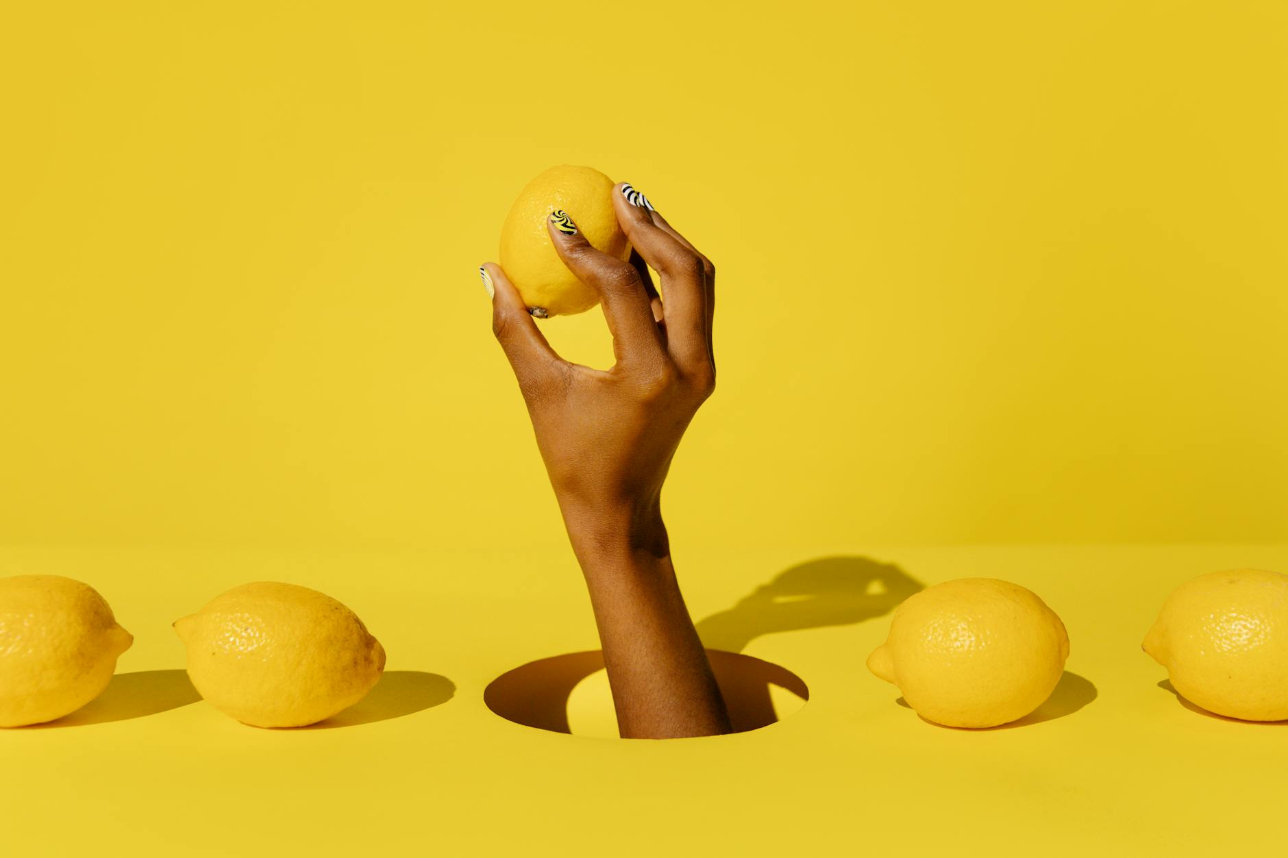 A hand holding a fresh lemon against a vivid yellow background, symbolizing the brightness and energy of solo pleasure at any age