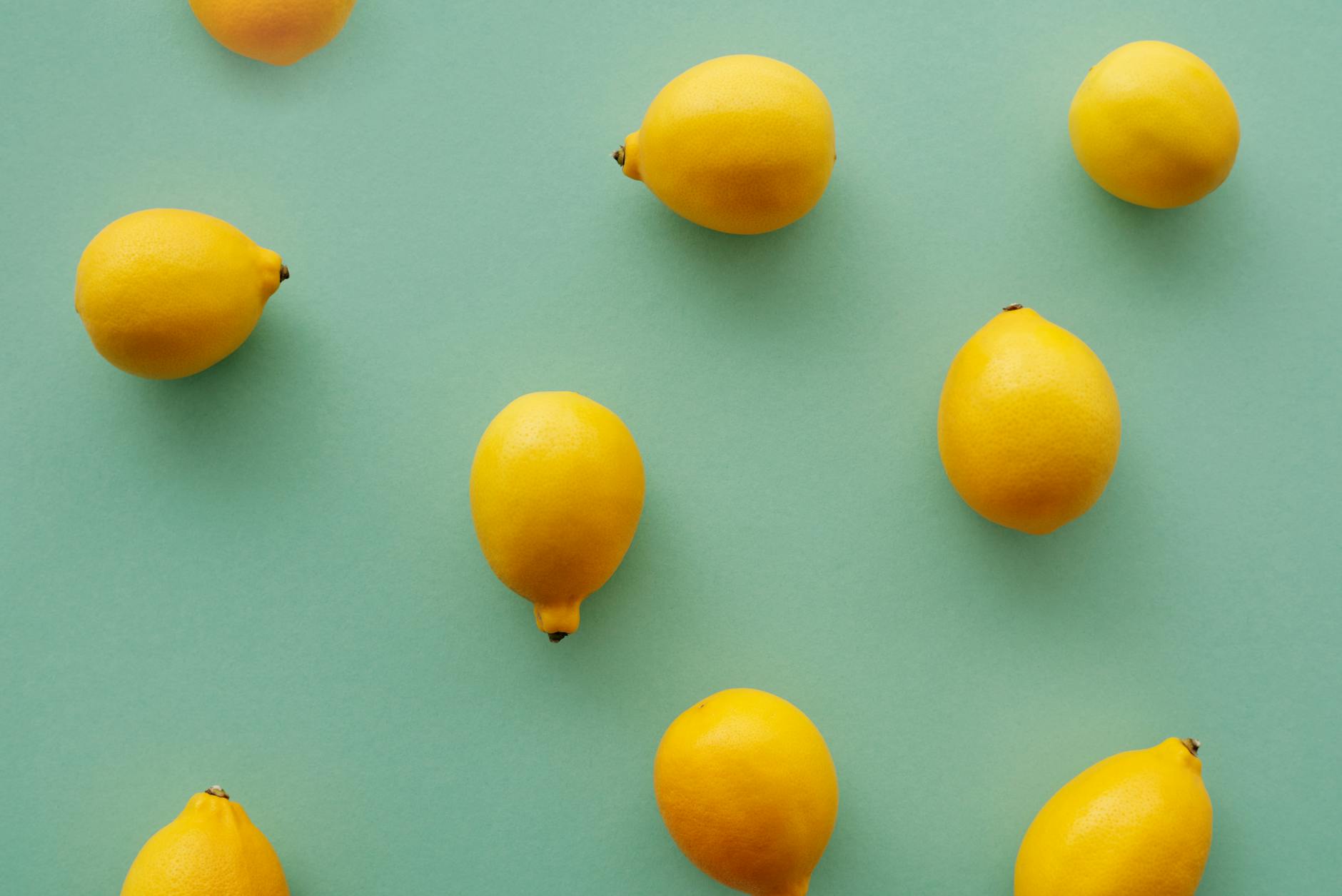 Bright yellow lemons arranged on a pastel green background, symbolizing fresh approaches to pleasure and sensation
