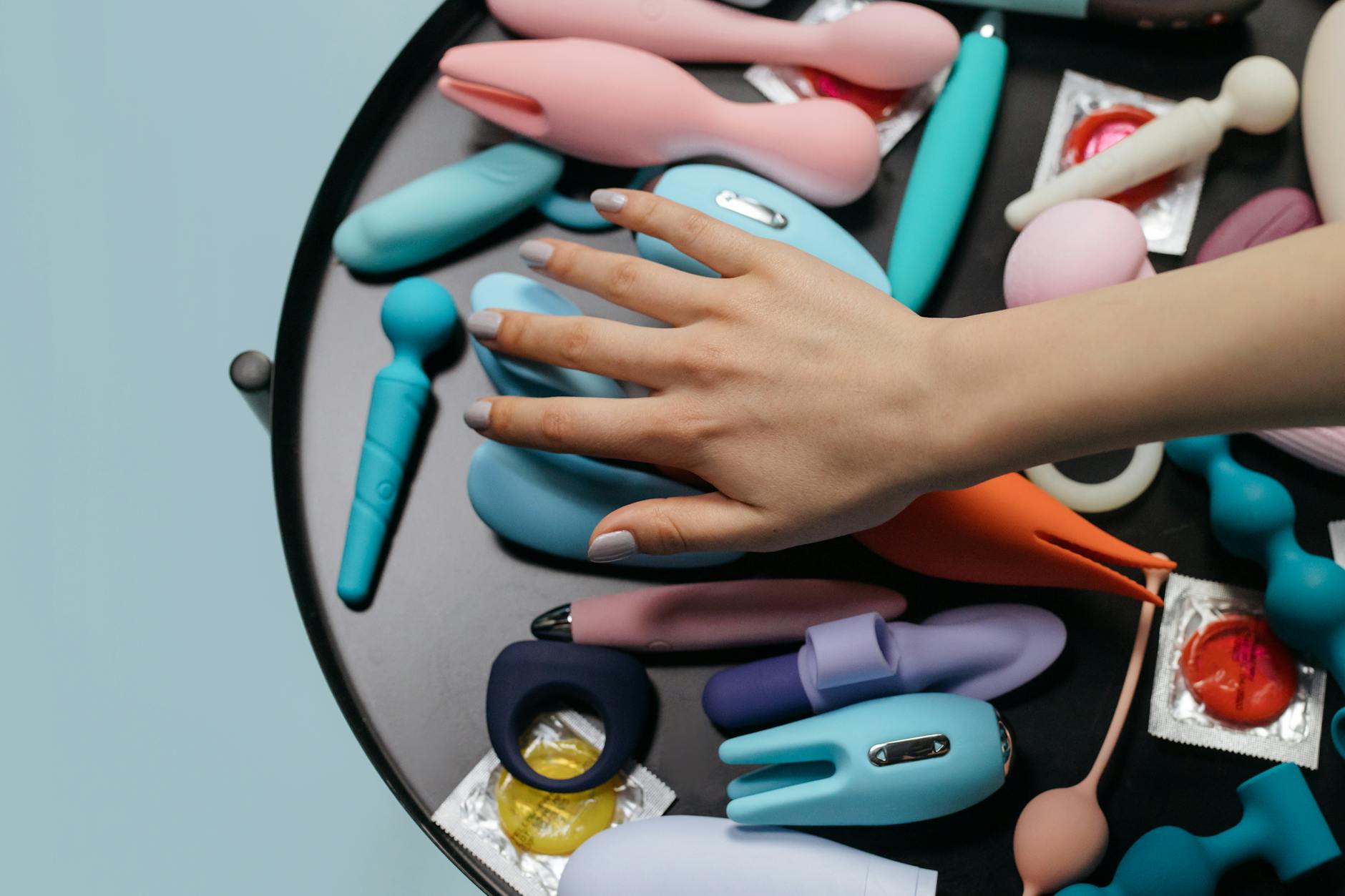 Close-up of hands holding a sleek blue vibrator, representing intimate communication without words