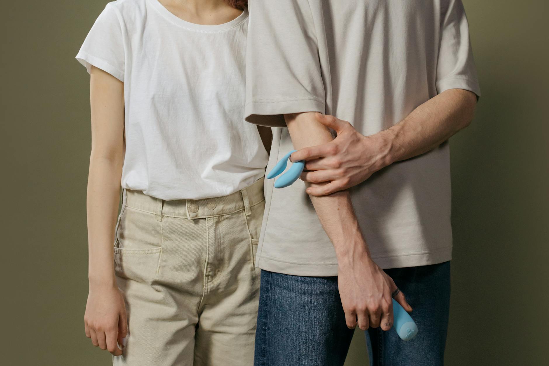 A young couple holding a blue vibrator together, representing intimacy and trust after healing.